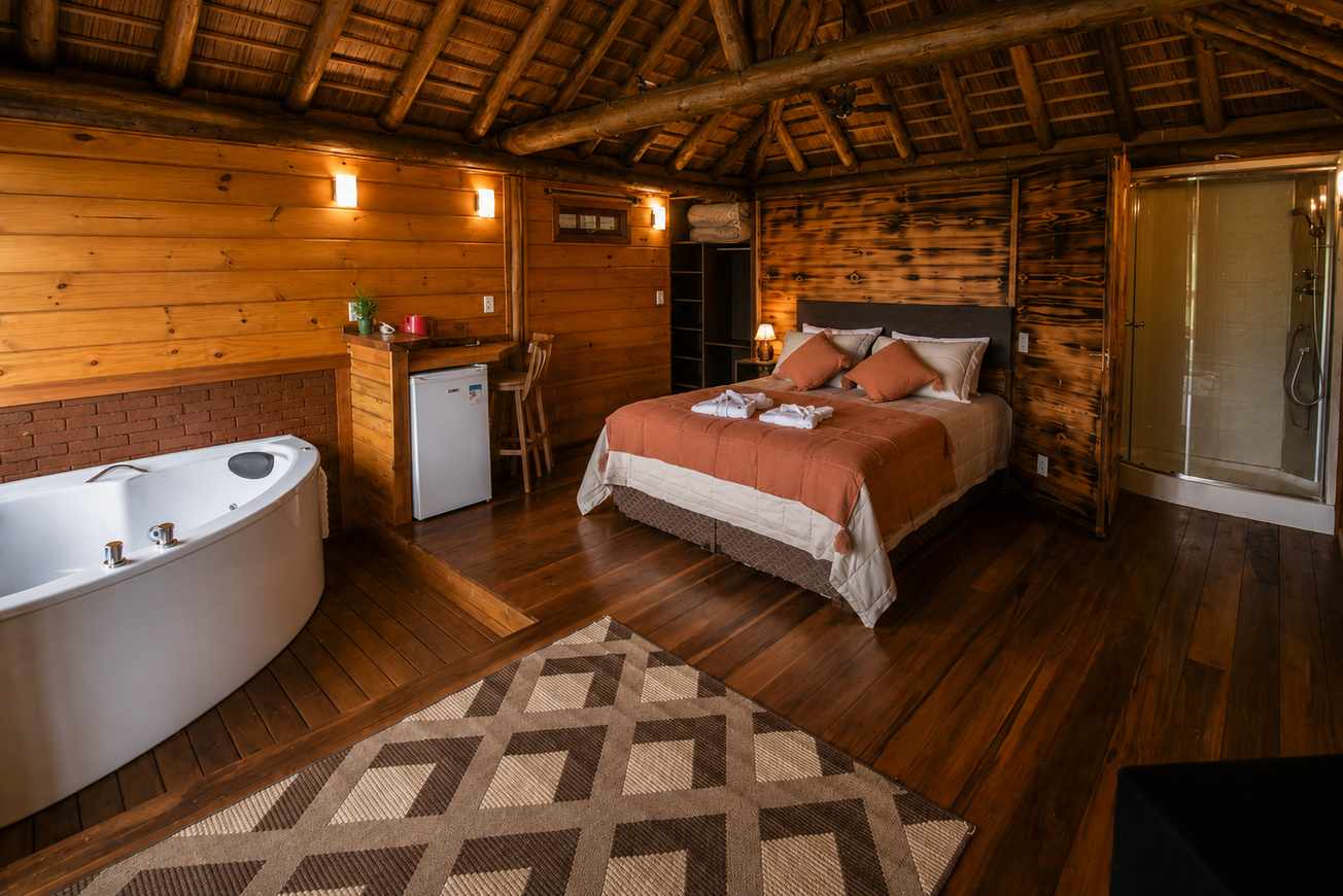 Queen room interior with warm timber finishes and spa bath at Refúgio Monte Itapeva